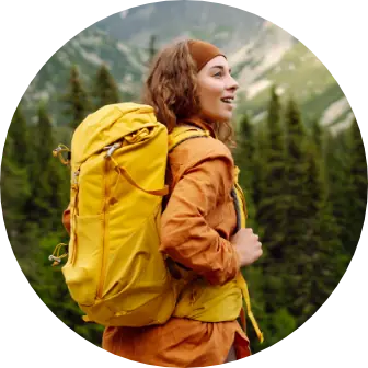 Kobieta z plecakiem na tle gór i lasu.