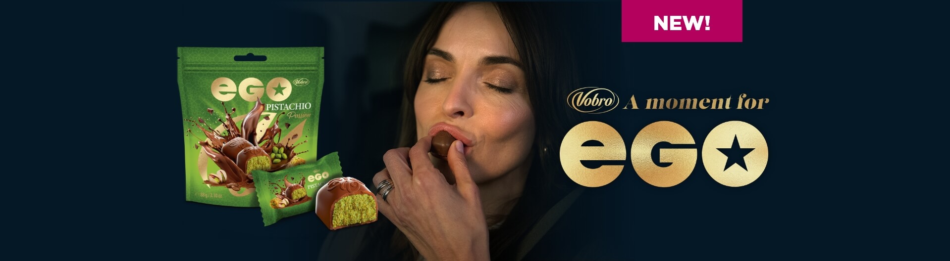 Advertisement for EGO Pistachio pralines by Vobro. A woman with her eyes closed places a chocolate praline into her mouth. Next to her, the green product packaging is visible, along with a cut-open praline revealing pistachio filling and the slogan: "NEW! Vobro A moment for EGO" set against a dark background.